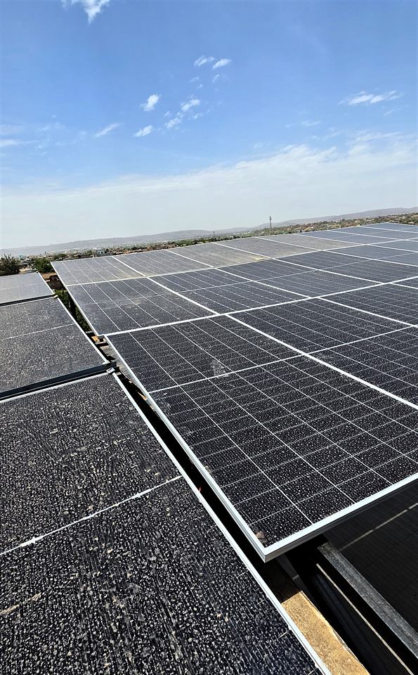 Modules solaires en toiture, surface légèrement poussiéreuse sous un ciel clair