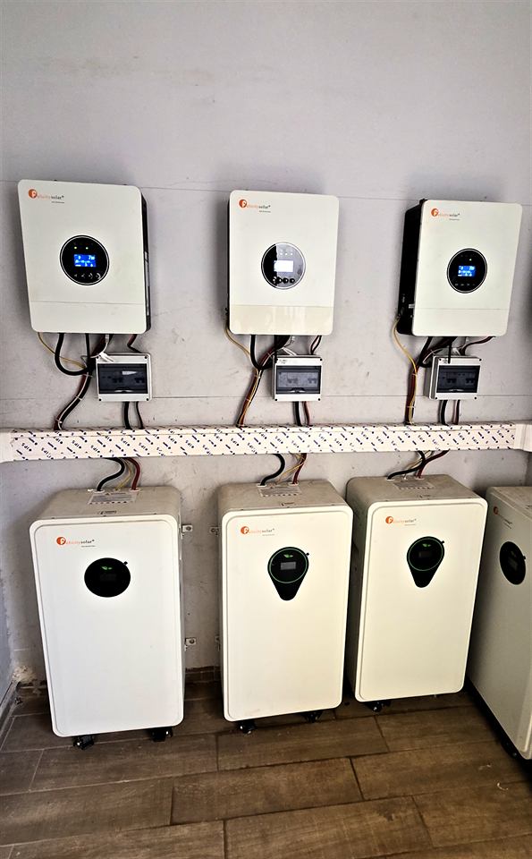 Trois onduleurs muraux alignés au-dessus de leurs batteries blanches