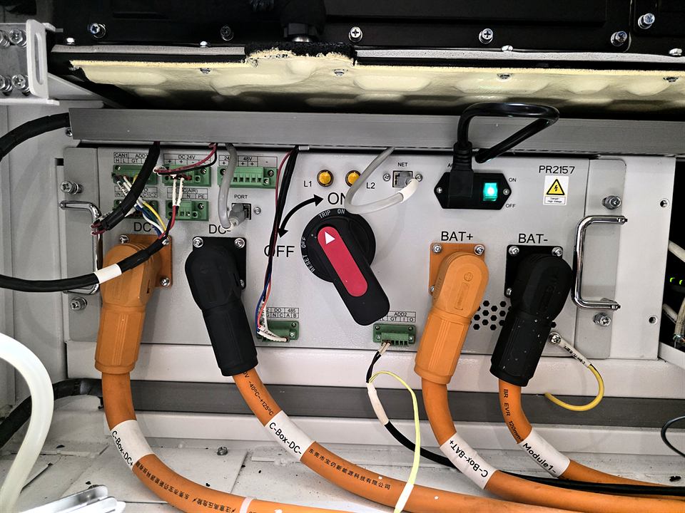 Câbles orange raccordés à un module de stockage, interrupteur rouge et connecteurs noirs