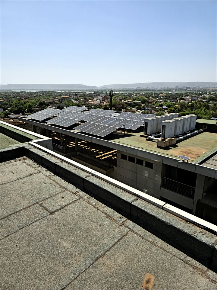 Modules solaires posés sur une toiture-terrasse, avec la ville en arrière-plan